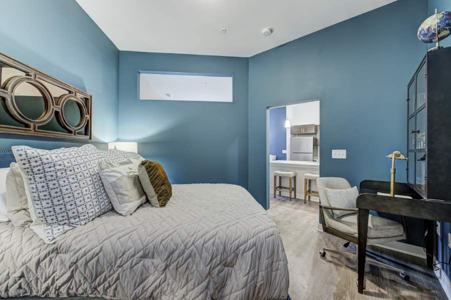 A small home office that flows with your design can be established anywhere, like in this bedroom at Midtown Flats. Apartment bedroom with a small desk and rolling chair